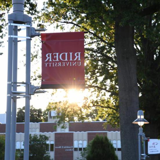 Rider sign at sunset in front of Moore library